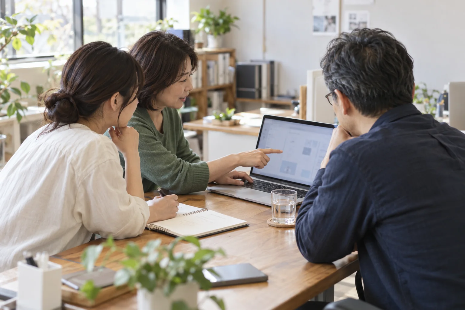 小さな職場でパソコンの使い方を一緒に確かめるイメージ